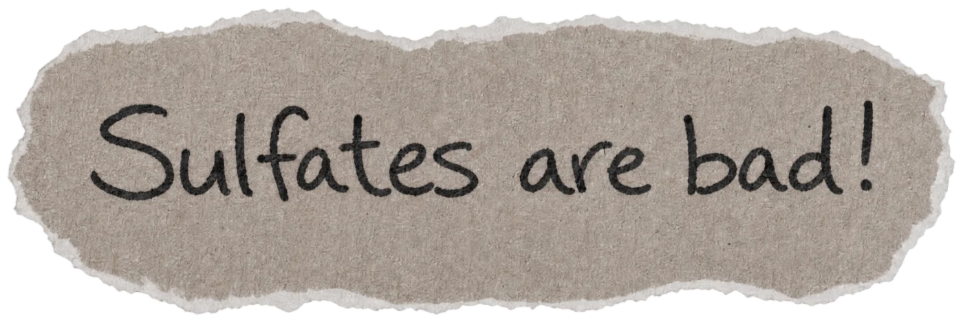 Torn paper note with the handwritten hair myth: Sulfates are bad!