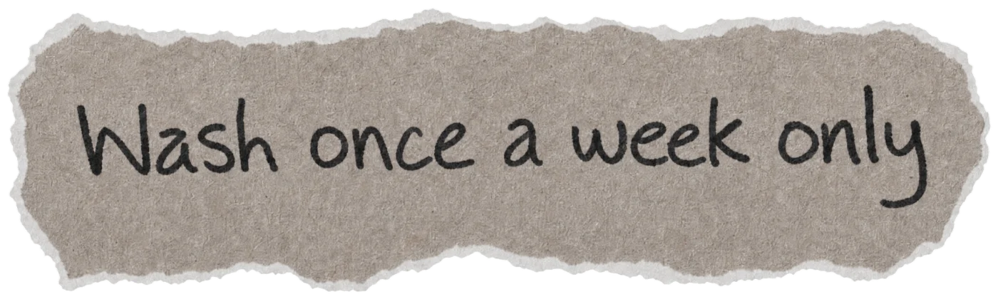 Torn paper note with the handwritten hair myth: Wash once a week only